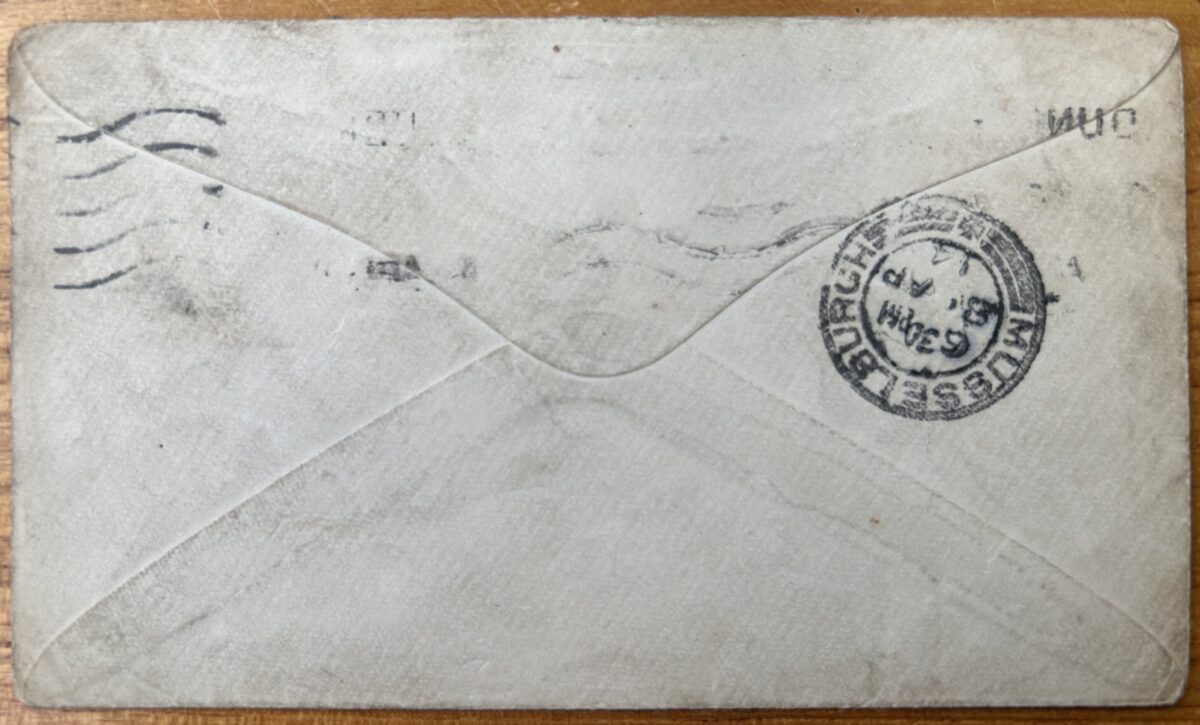 Reverse of a well-worn paper envelope with crossed triangular flaps and faint postal cancellation marks. A circular Musselburgh postmark is visible on the right-hand side, with creases, stains, and signs of age across the surface.