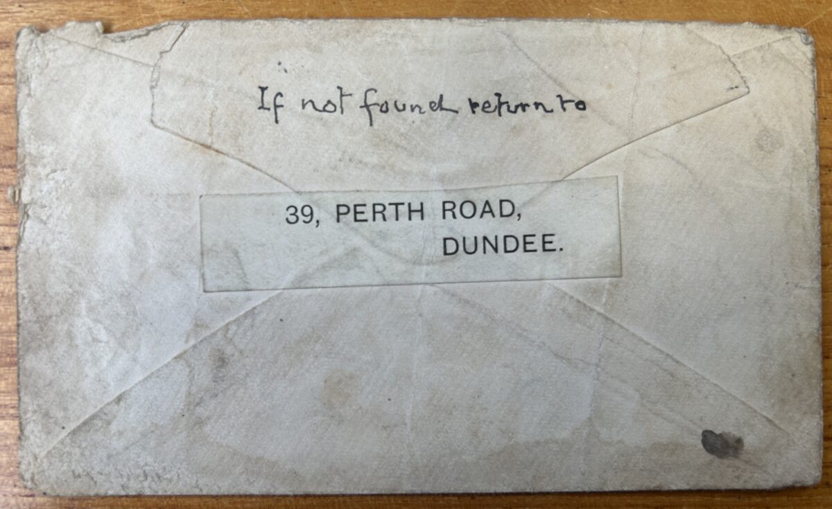 Reverse of a worn paper envelope with a handwritten note reading “If not found return to” above a printed return-address label: “39, Perth Road, Dundee.” Creases, folds, and surface wear are visible across the envelope.